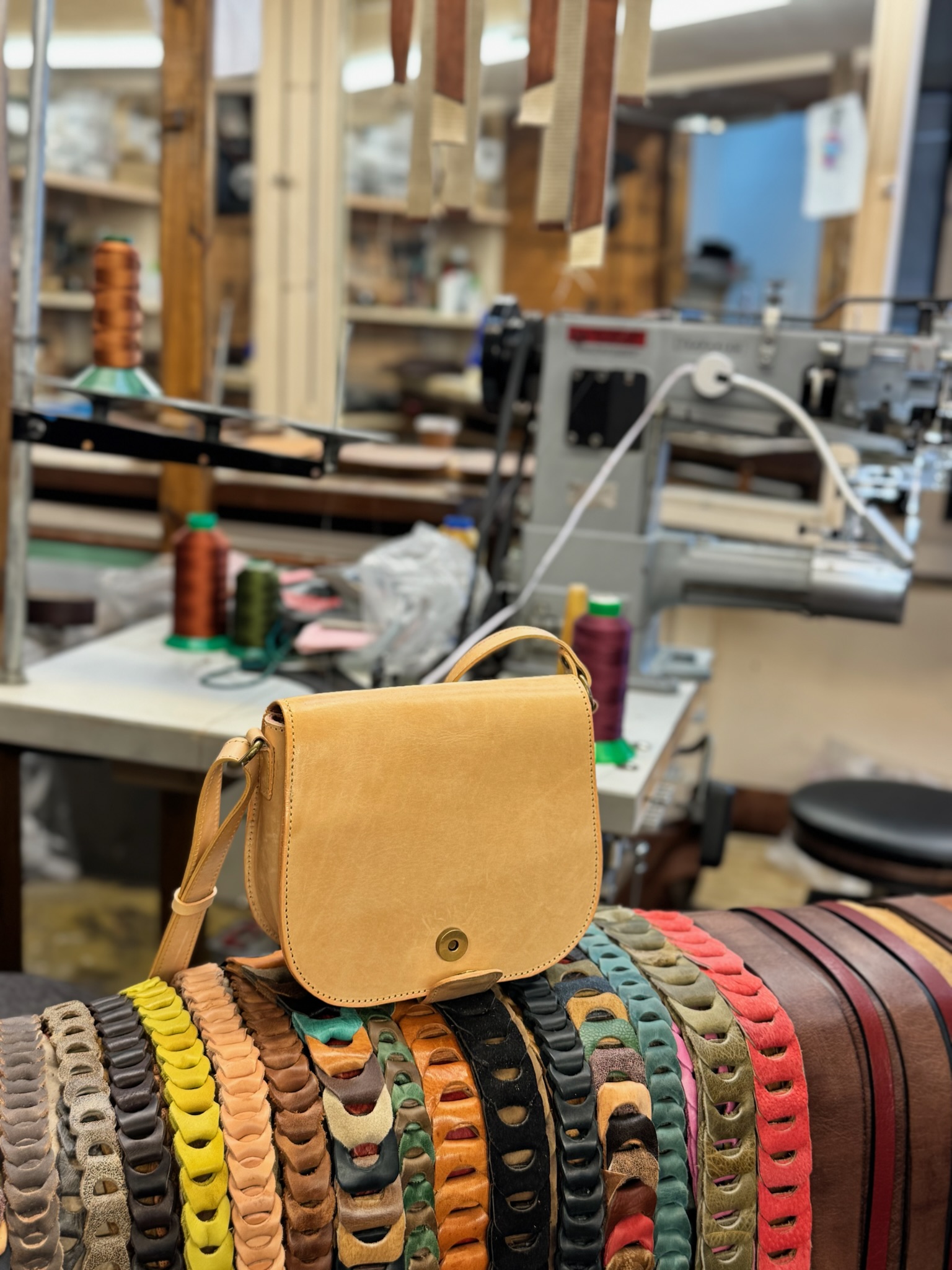 Handcrafted vegetable-tanned leather saddle bag on coloured leather swatches in a European artisan workshop — Old Continent Atelier Athens I collection